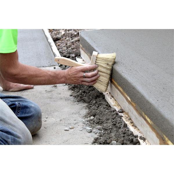 Person using a MARSHALLTOWN masonry brush on wet concrete