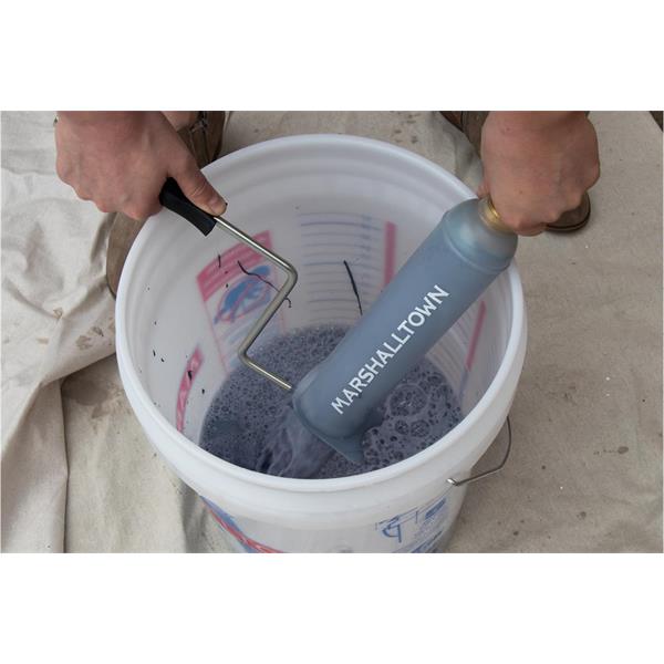 Hands using a MARSHALLTOWN roller cleaner in a bucket