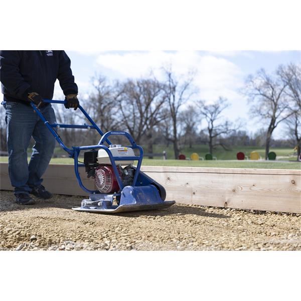 Person operating a MARSHALLTOWN vibratory plate compactor on gravel surface