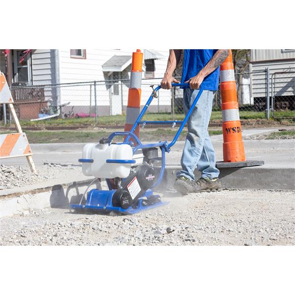 Person operating MARSHALLTOWN vibratory plate compactor with water tank on gravel surface