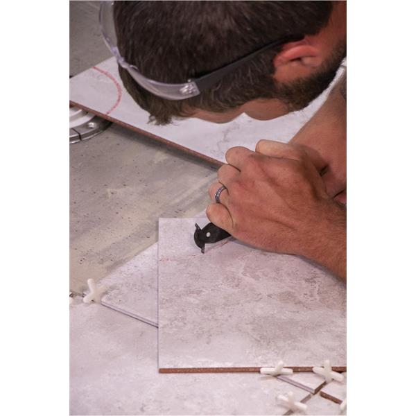 Person using a MARSHALLTOWN scoring knife on tile surface