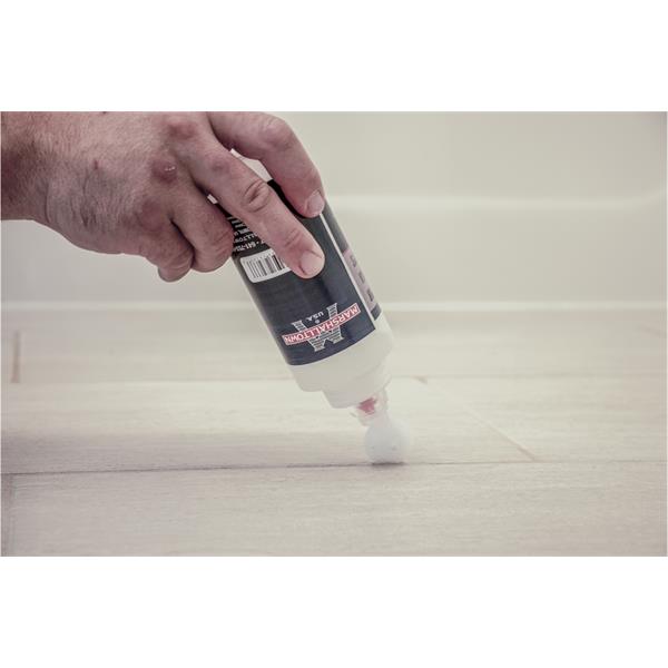 Hand applying grout sealer with a MARSHALLTOWN bottle