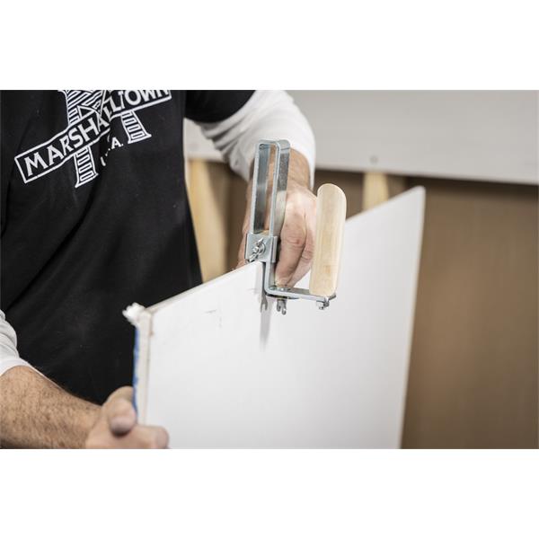 Person using a MARSHALLTOWN drywall stripper on a drywall sheet