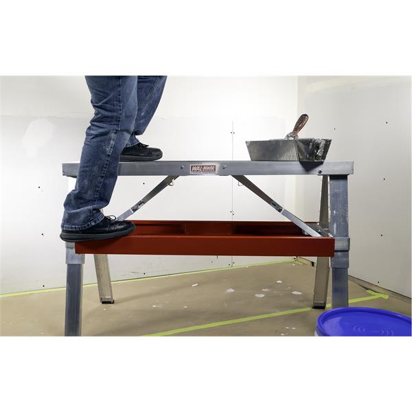 Person standing on a WAL-BOARD TOOLS aluminum folding bench for construction tasks