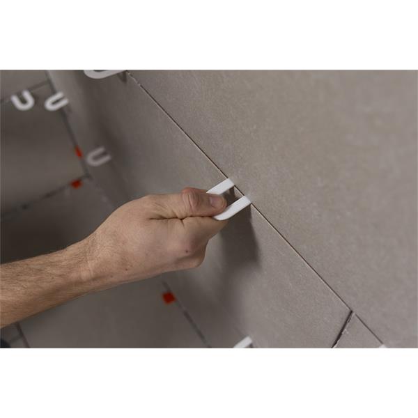 Hand positioning BARWALT horseshoe spacers between tiles