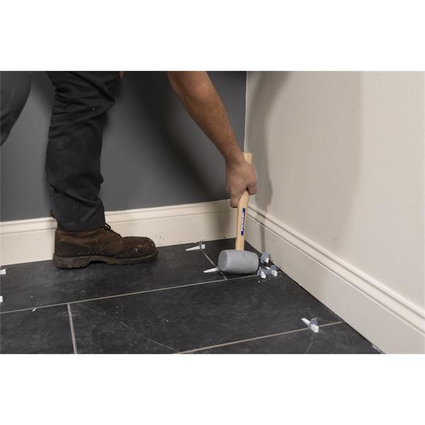 VAUGHAN Solid Rubber Mallet with wooden handle being used on floor tiles.