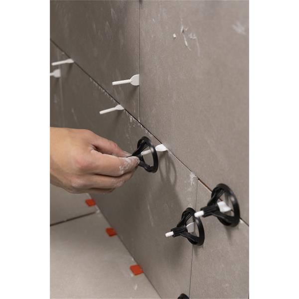 Hand using BARWALT PLS Revolve Tile Leveling System on wall tiles