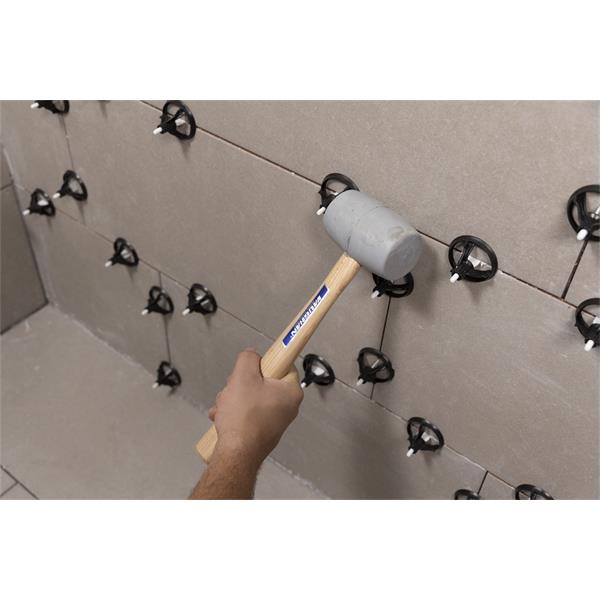 Hand using BARWALT PLS Revolve Tile Leveling System on tiled wall